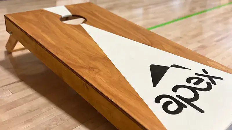 a wooden cornhole board with a white triangle on it