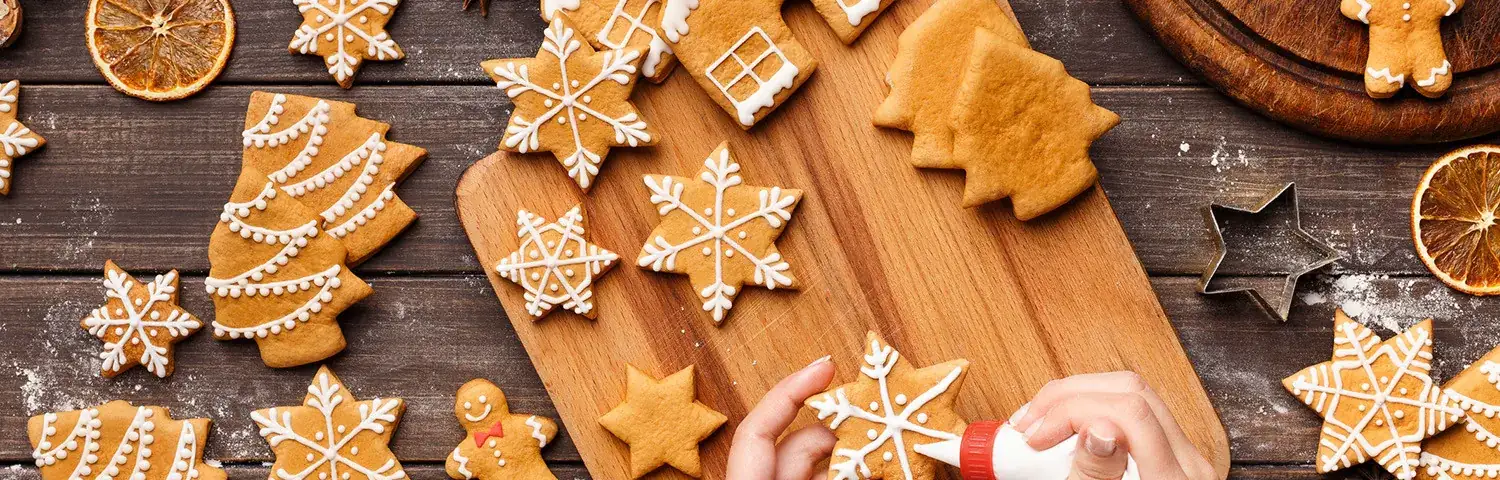 Icing process of Christmas bakery Unrecognizable woman decorating homemade cookies