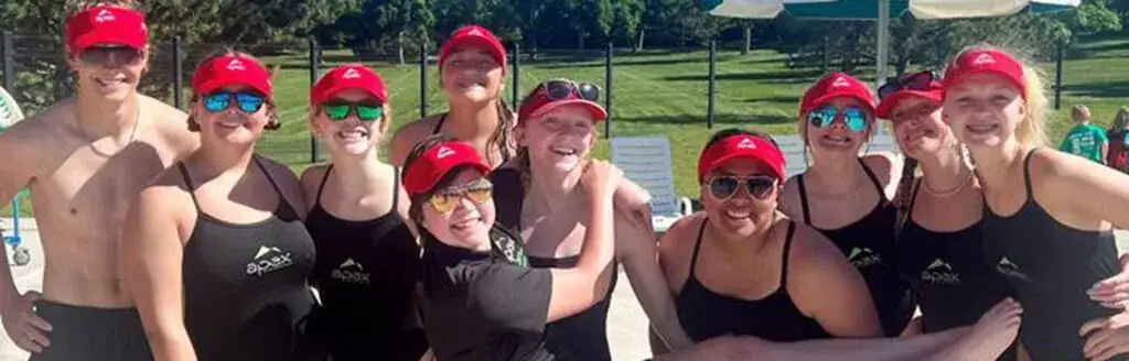 A group of people in matching red caps and swimwear.