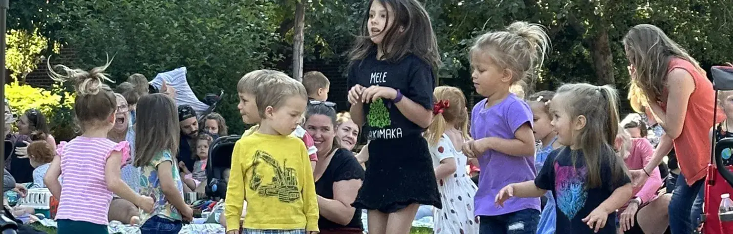 A group of children dance joyfully outdoors.