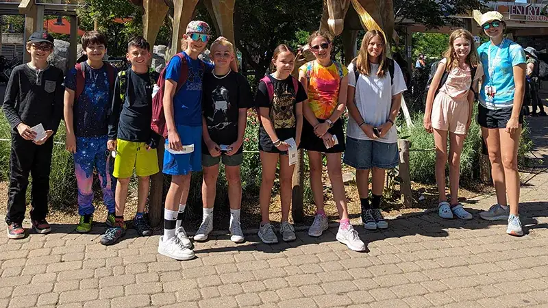 A group of nine children stand together outdoors.