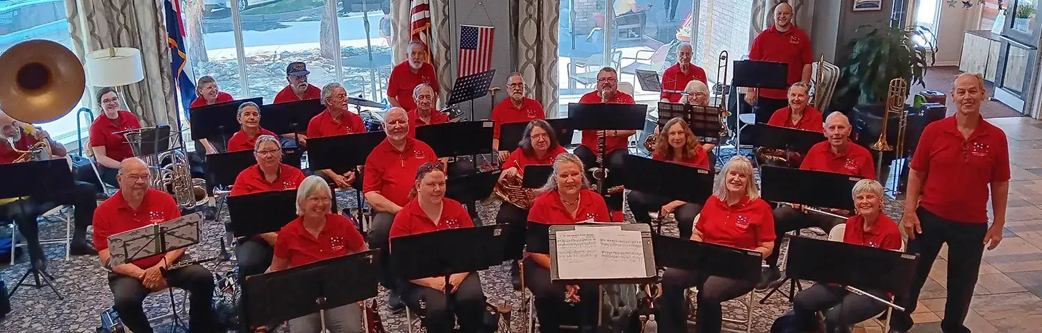 A group of individuals wearing red shirts, holding musical instruments.