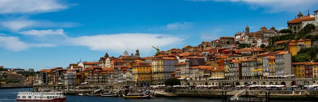 Panoramic view of Porto's riverside with colorful buildings and boats.