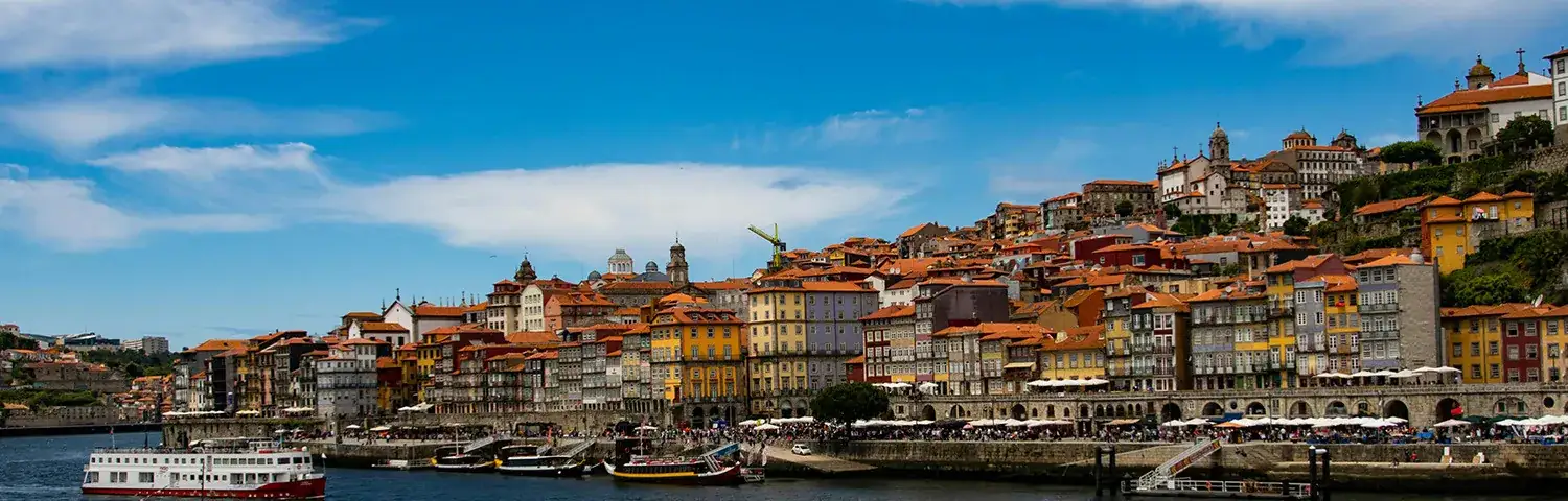 Panoramic view of Porto's riverside with colorful buildings and boats.