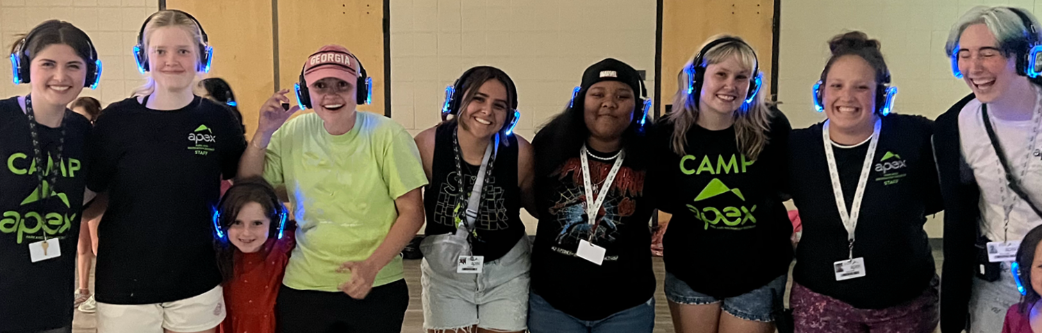 Group of people wearing glowing blue headphones posing indoors.
