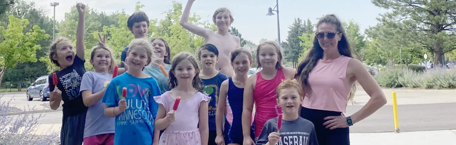 Group of kids and an adult posing outdoors.