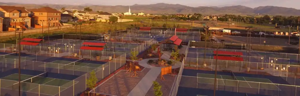 Aerial view of a sports complex with multiple fenced pickleball courts.