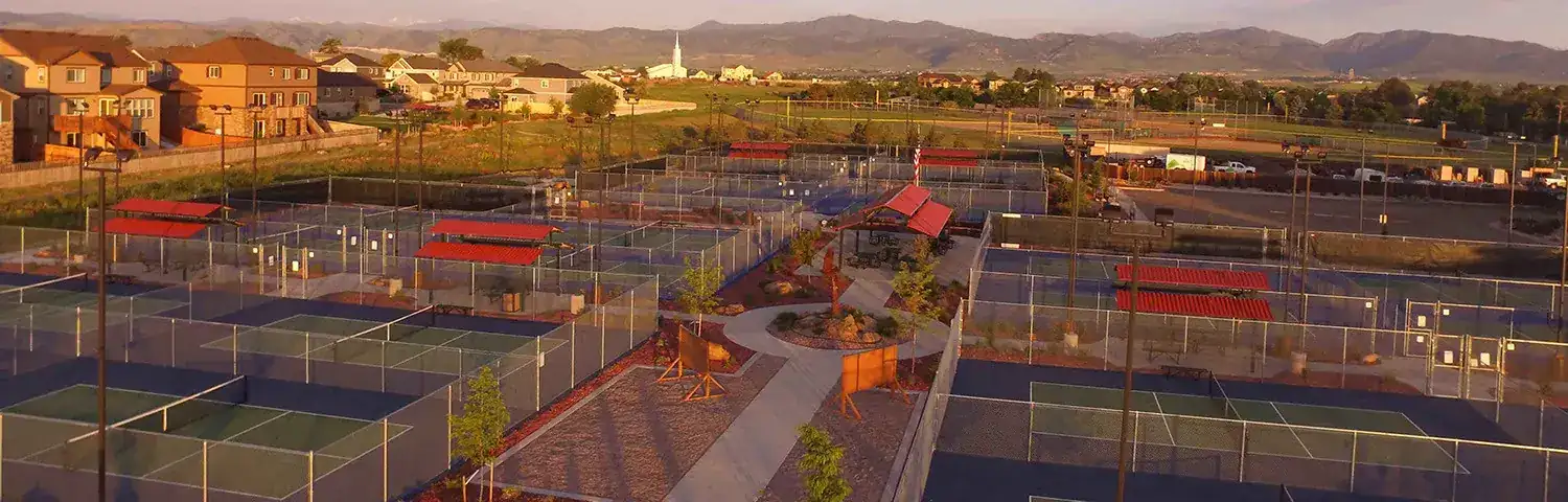 Aerial view of a sports complex with multiple fenced pickleball courts.