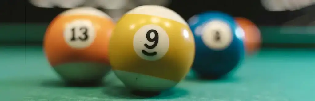 Yellow and white striped 9-ball in focus on a green pool table.