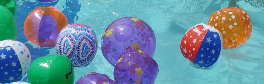 Colorful patterned inflatable balls floating on water.