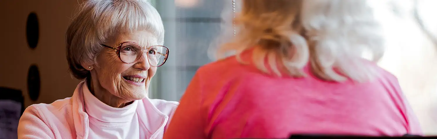 Speed Friending banner Senior women sharing a joyful conversation over coffee in a cozy indoor setting.