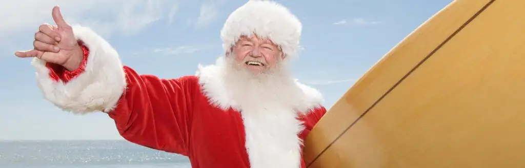 Santa Claus Gesturing With Surf Board On Beach