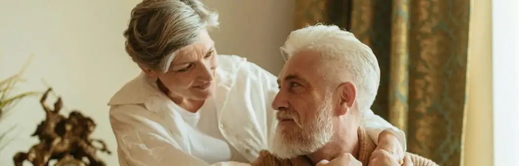 Older woman and man embracing as they look into each other’s eyes with smiles.