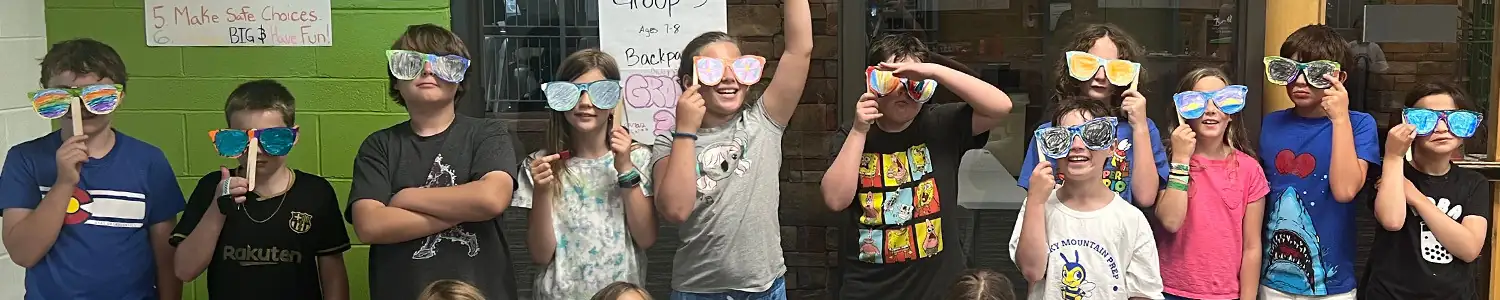 Group of children wearing colorful oversized novelty sunglasses.