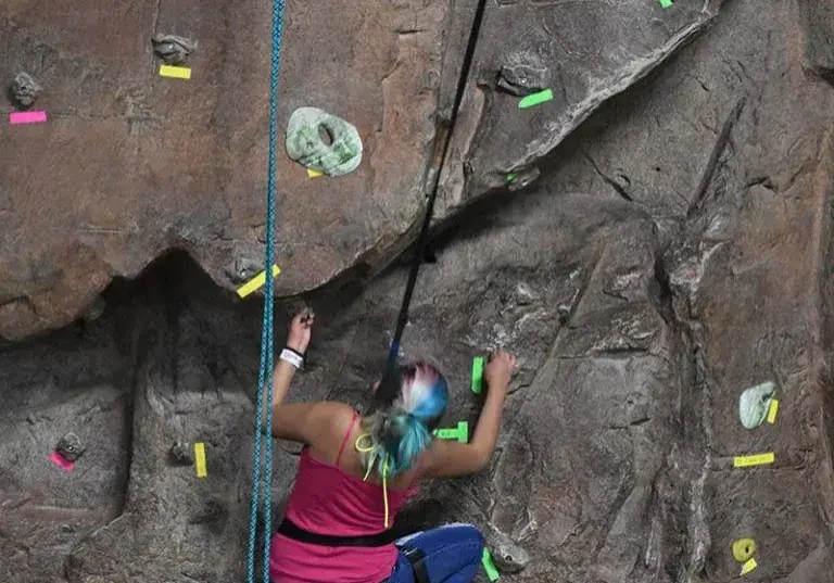 A woman climbing up the side of a rock wall